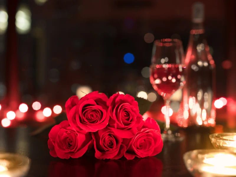 red roses on table with a glass of wine
