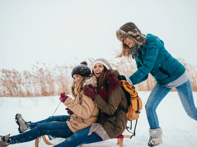 group of three friend on a sled, snow covered ground